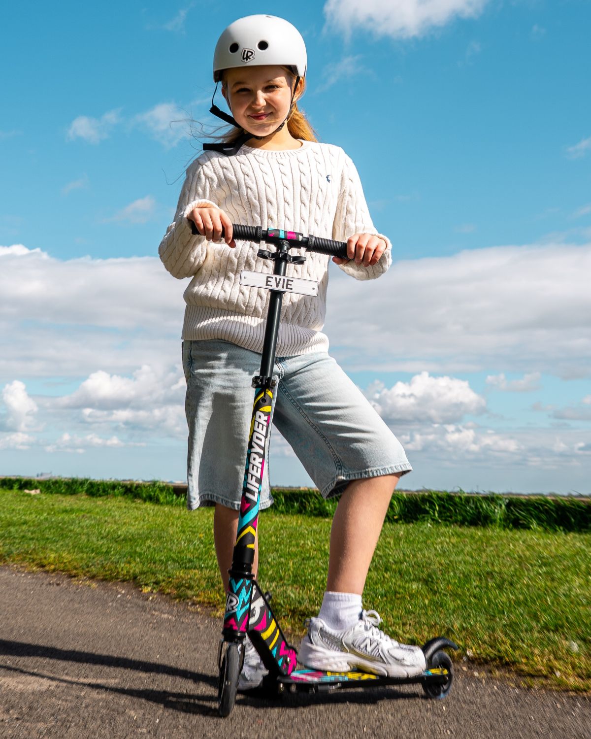 Child posing with a LIFERYDER QUEST 2 wheel scooter against a blue sky