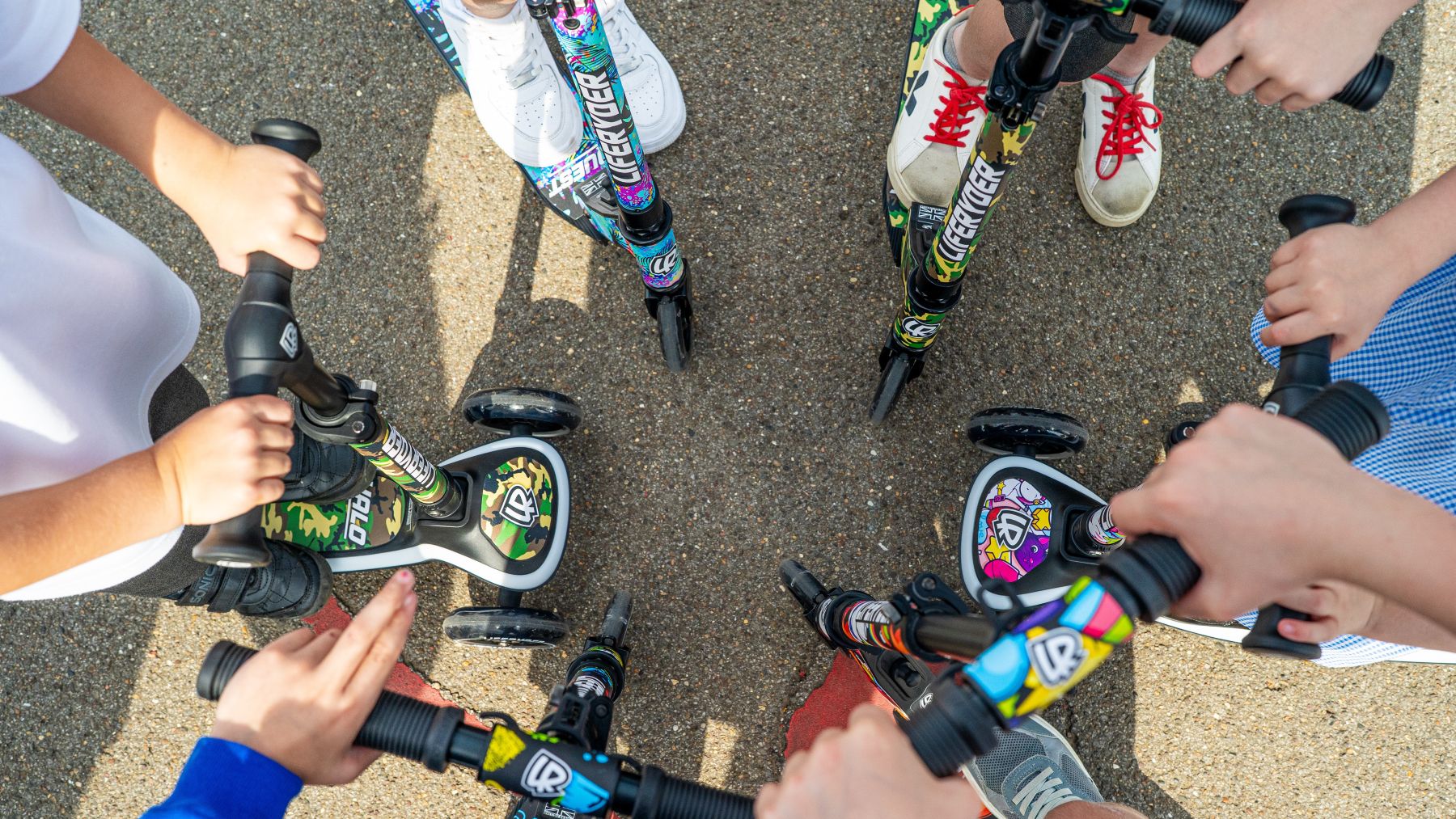 Children with LIFERYDER scooters featuring colourful EVOLV sticker designs