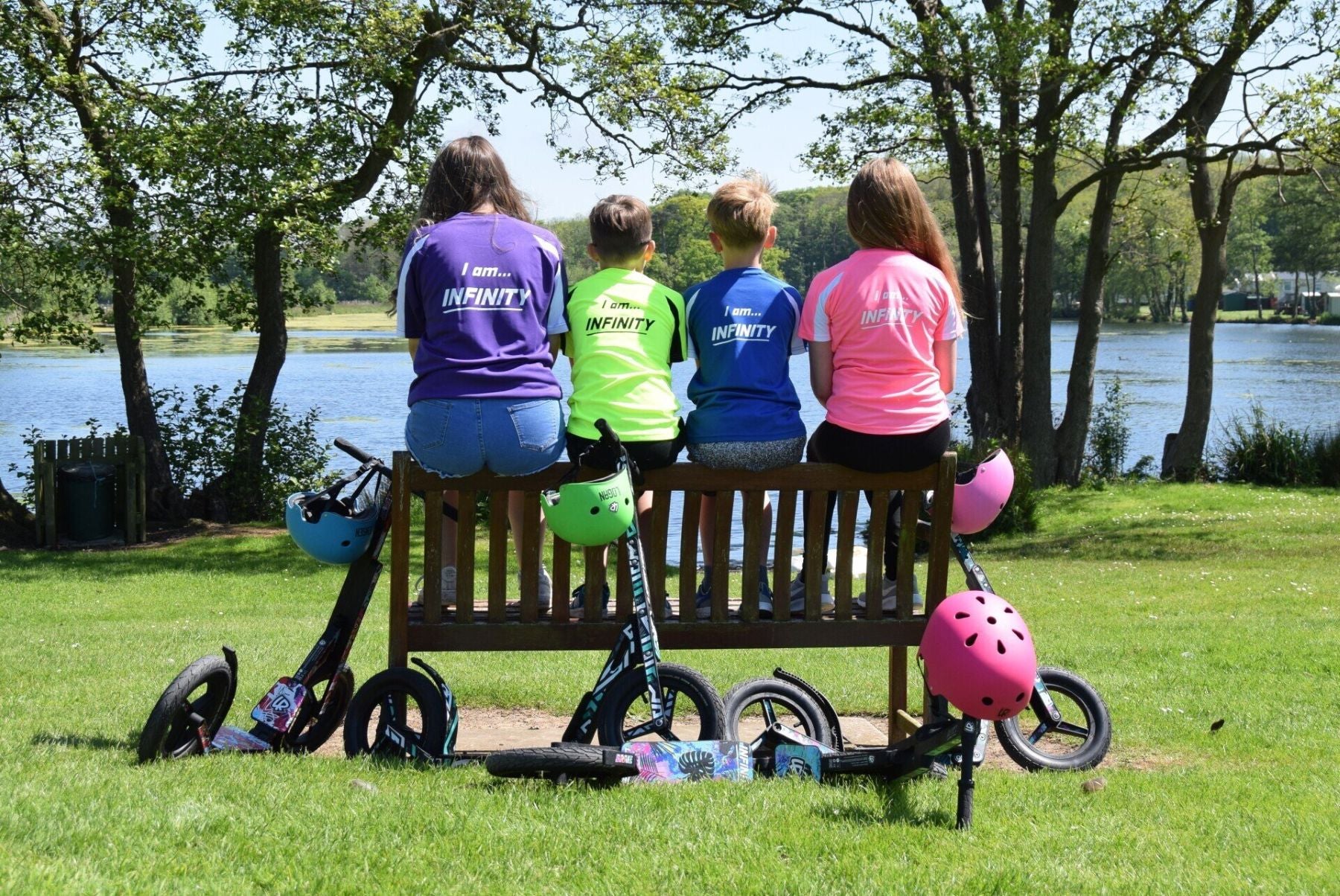 Children sitting with LIFERYDER scooters and accessories on a bench