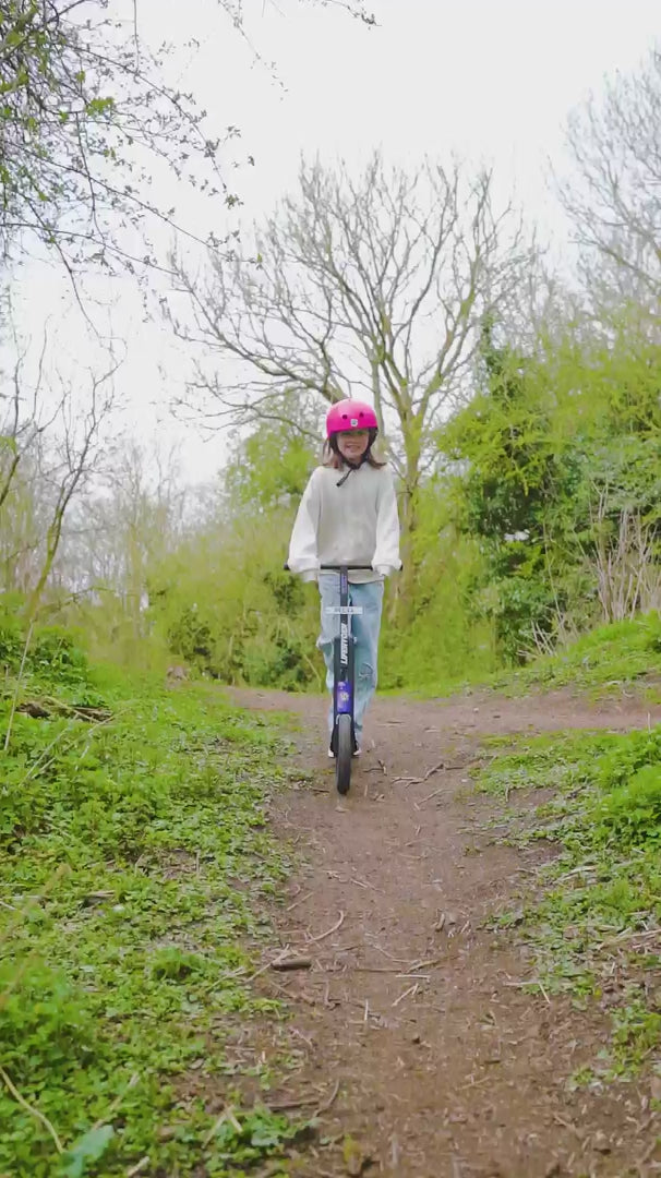 Child riding a LIFERYDER INFINITY big wheel scooter through woodland